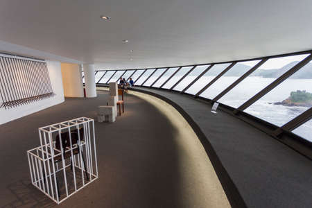 Interior of Niteroi art museum with works of art and people sitting and looking at it