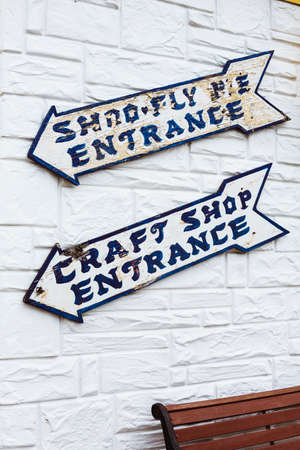 two arrow shaped entrance signs on white brick wallの写真素材