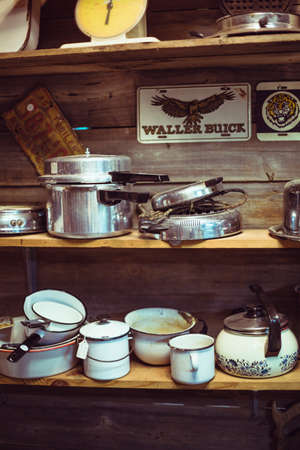 wooden shelves in thrift store cluttered with old pots and pansのeditorial素材