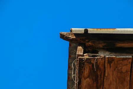 The cecayed woodden of corner roof with blue sky backgroundの写真素材