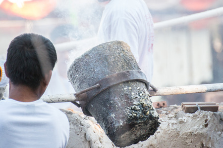 Worker pouring molten metal to casting Buddha statueの写真素材