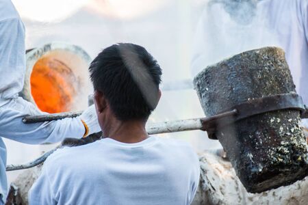 Worker pouring molten metal to casting Buddha statueの写真素材