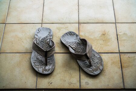 Old rubber sandal with tiger striped on dirty tile backgroundの写真素材