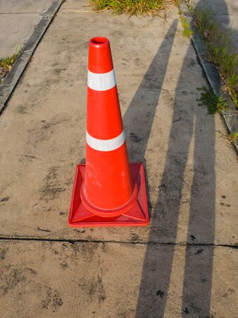traffic cone, with white and orange stripes on gray asphalt, copy spaceの写真素材