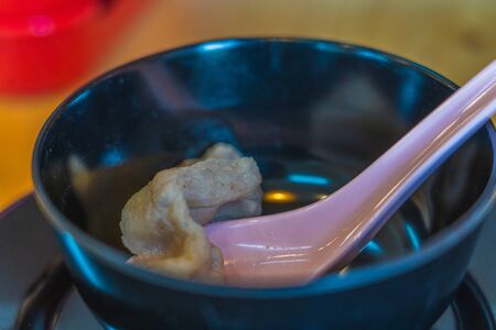 Spoon with boiled pork for eat in black bowlの写真素材