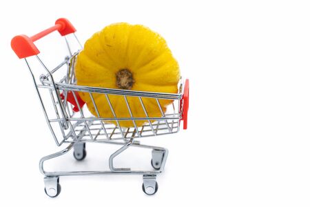 A Fresh orange pumpkin in shopping cart on isolated white backgroundの写真素材