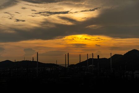 The Oil Or Gas Refinery At Sunset. A silhouette of an oil or gas industrial refinery at sunset with a colourful sky behindの写真素材