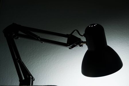 The Silhouette of a table lamp on the background of a window in the morning at dawn, work until morning, work at night.の写真素材