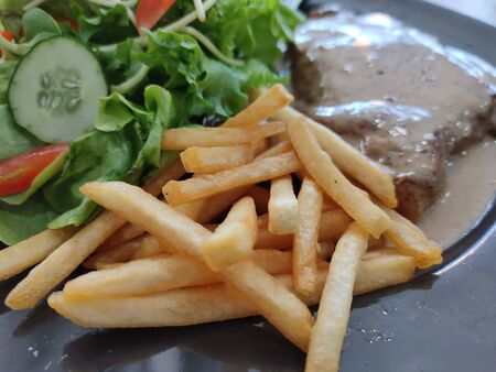 The Selected focus on french fried with Steak ,salad on black diskの写真素材