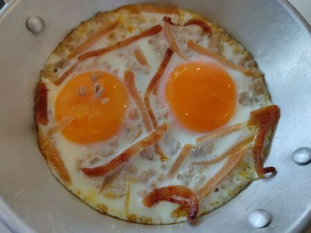The Fried eggs in a frying pan with cherry tomatoes and bread for breakfast on a steel background.の写真素材
