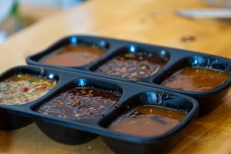 The Spicy sauces and condiments for Shabu in cup of sauce on a wooden table background.dipping sauce for shabu.の写真素材