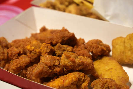 Fried breaded chicken fillet in white cardboard box isolated on burred backgroundの写真素材