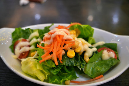 Healthy vegetable salad of fresh tomato, cucumber, onion, spinach, lettuce and sesame on plate. Diet menu.の写真素材