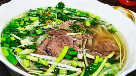 Closeup of traditional Vietnamese pho soup with meat and vegetables (selective focus)