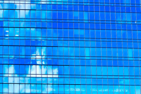 Facade of a glass and metal skyscraper with blue and white reflections