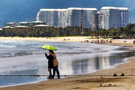 Hainan Shenzhou Peninsula, China - February 13, 2017: Couple with sun umbrella made selfie near the tropical beach of Hainanのeditorial素材