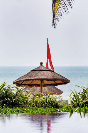 Glimpse of the pool and tropical sea with wooden sunshadeの写真素材