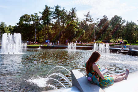 Moscow, Russian Federation - August 2, 2017:  Sokolniki Park woman reads book on the edge of the fountain, she enjoys the summer day of  Mariners of the Navy armyのeditorial素材