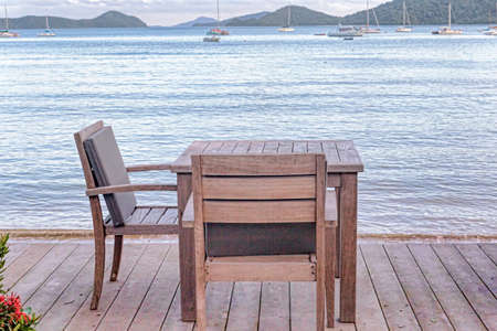 Wooden table and chairs with ocean viewの写真素材