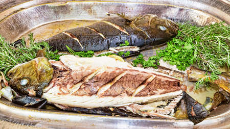 Roasted fish with oregano and parsley in selective focus