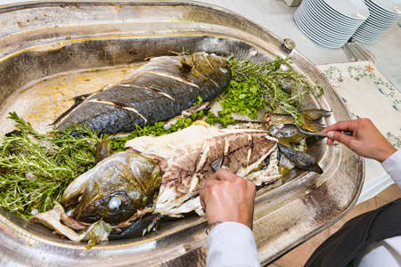 The chef fillets two big roasted fish