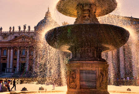 Vatican City,Vatican State - July 19, 2018: The ancient fountain surrounded by tourists enjoy the beauties of St. Peter's Square. St. Peter's Square is located in front of St. Peter's Basilica in the Vatican City.のeditorial素材