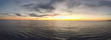 Amazing golden hour sunset panorama with the sky streaked with clouds