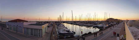 Ostia Lido Rome, Italy - January 15, 2019: Sunset panorama in golden hour at tourist harbor in Rome, Many sailboats are moored, some people look at the landscape and walk around.のeditorial素材