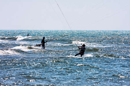 Lido dei Pini, Italy - April 25,2014: On the Roman sea of Lido dei Pini beach athletes performs kitesurfing between waves and foam, a perfect day with rough sea and weather conditions necessary for this sport.のeditorial素材