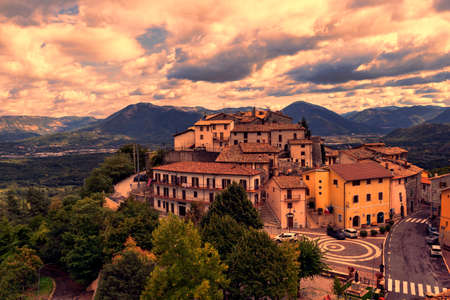 Suggestive sunset at fairy-tale medieval village lost in wilderness area of mountains and woods with fantastic cloudy sky and dramatic lightのeditorial素材