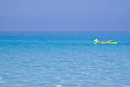Woman on green mat in sea on vacation