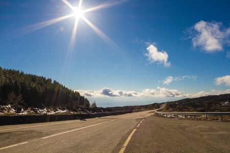 Long, lonely road in front of blue sky and mountainsの写真素材
