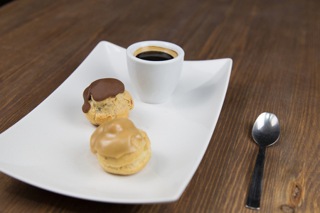 bignè and coffee on white white dish on wooden table