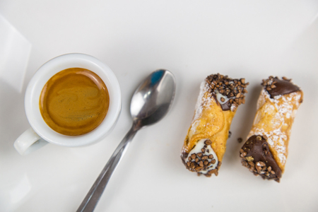 Sicilian Cannoli and coffee on white dish on wooden tableの写真素材