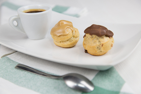 bignè and coffee on white dish on wooden table