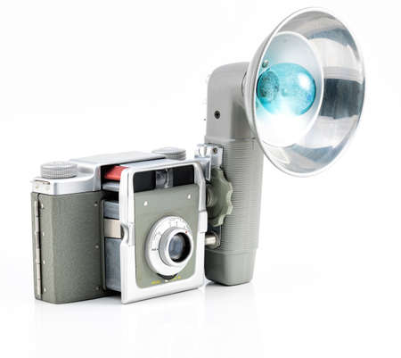 Vintage camera on white background that has a flash accesorie with a blue lightの写真素材