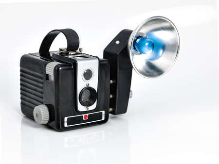 Vintage camera on white background that has a flash accesorie with a blue lightの写真素材