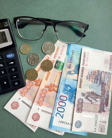 Cash notes, coins, points and calculator on a green background