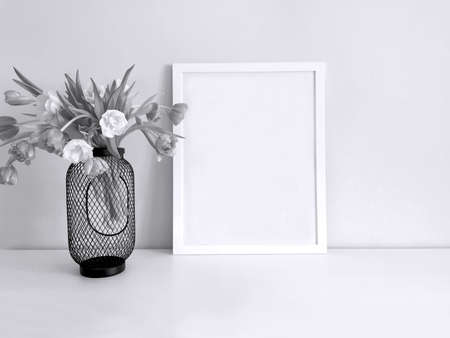 Template of a vertically placed white picture or photo frame on a white table with a bouquet of...