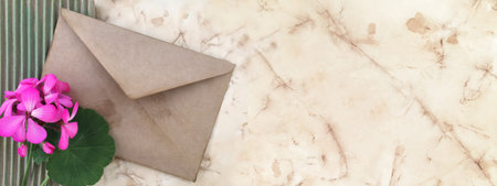 Pink flower with a brown postal envelope on the background of old paper. Space for text.の写真素材