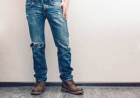 Young fashion man's legs in jeans and boots on wooden floorの写真素材