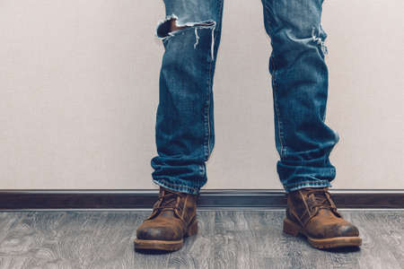 Young fashion man's legs in jeans and boots on wooden floorの写真素材
