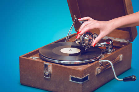 Old portable gramophone with female hand pin-up styled isolated, on blue background with empty space