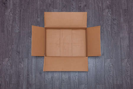 Flat lay of empty open cardboard box on wooden surface