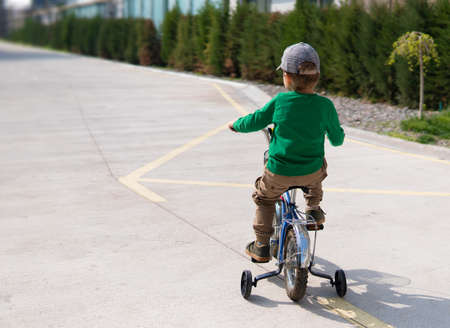 Small boy cycling on a little training bike on the road