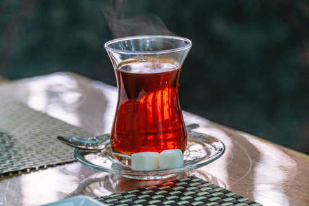 Closeup of traditional Turkish glass cup, bardak, of Turkish black tea with sugar and spoon