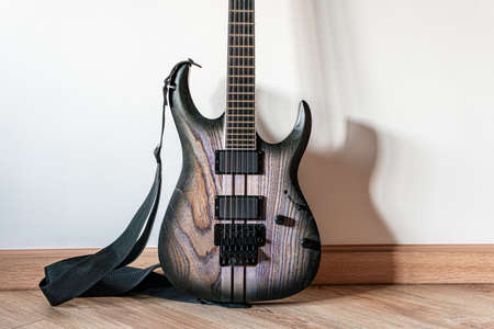 Electric wooden guitar laying on floor in front of white wall with copy-space