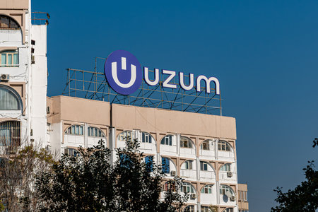 NOVEMBER, 08 - Tashkent, Uzbekistan: a sign reading Uzum displayed on a building under a clear blue sky, surrounded by greenery, showcasing urban architecture.のeditorial素材