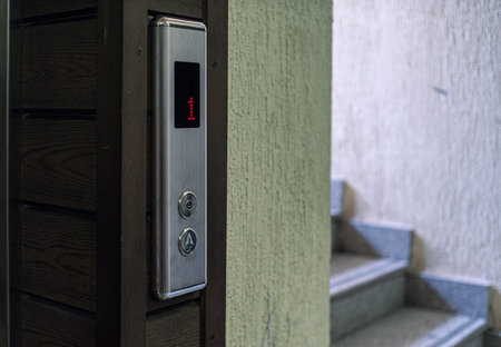 A close-up of an elevator control panel displaying the number one, with stairs visible in the...