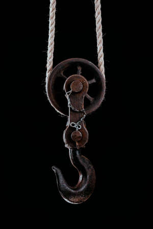 Big metal hook hanging on rope isolated on black background.の写真素材